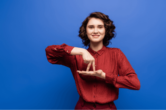 A woman with medium, curly hair signing in ASL