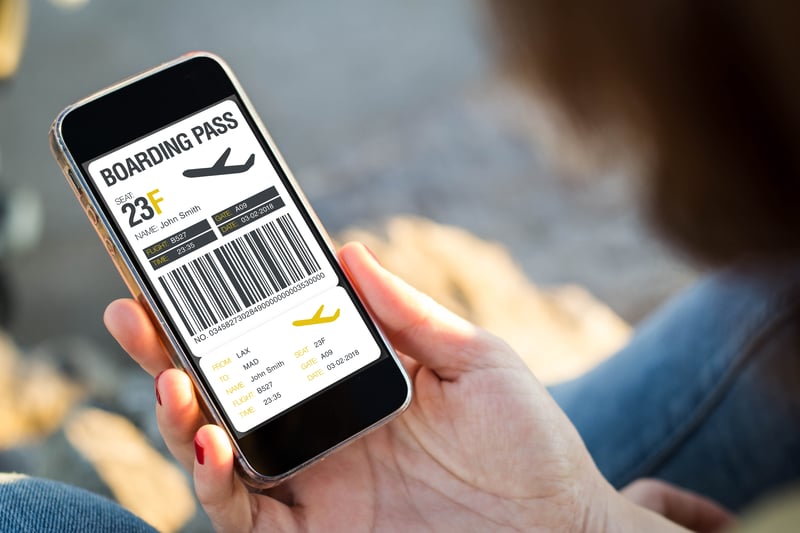 A person holding a phone with their boarding pass information displayed.