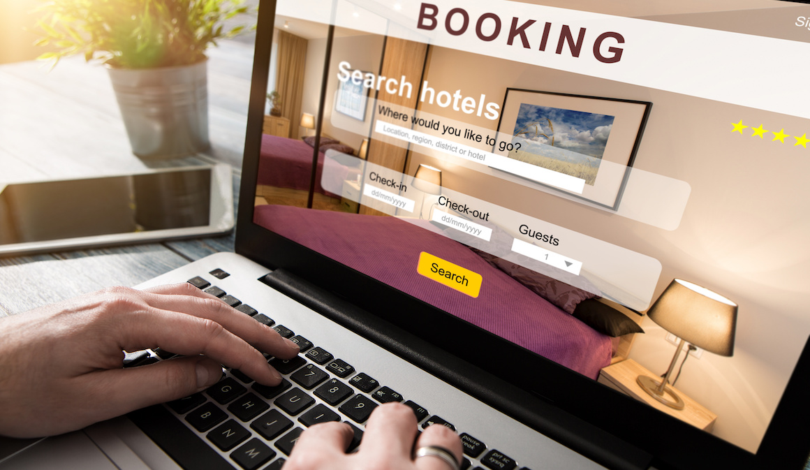 Person booking hotel stay on website using laptop 