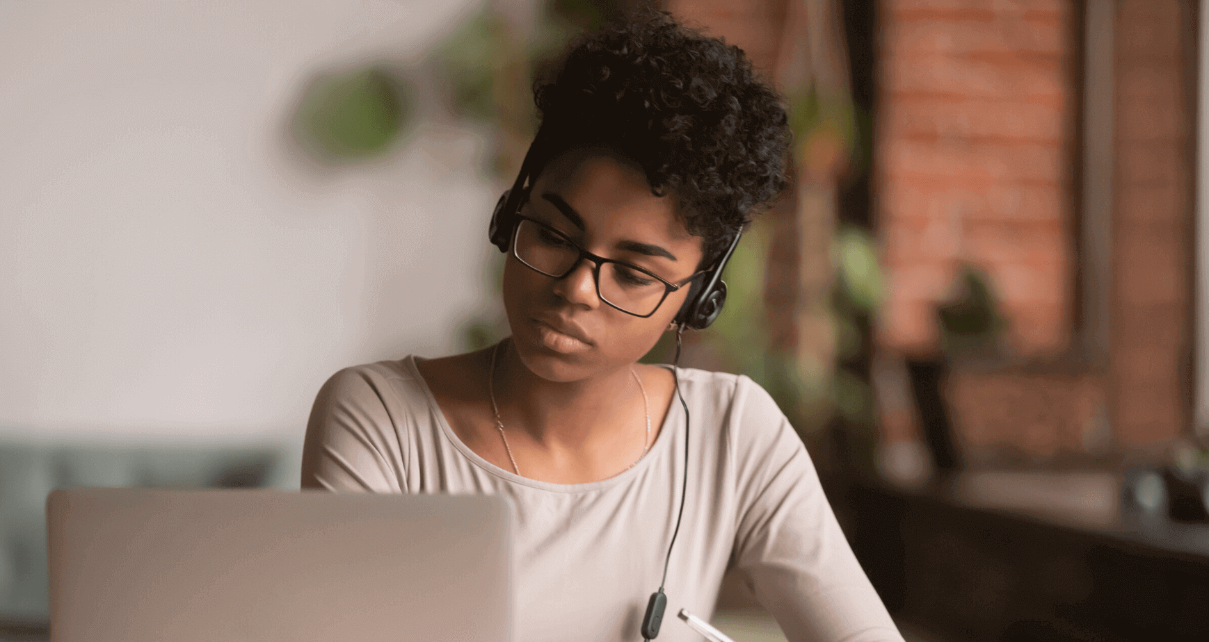 A woman wearing headphones and looking at her computer.