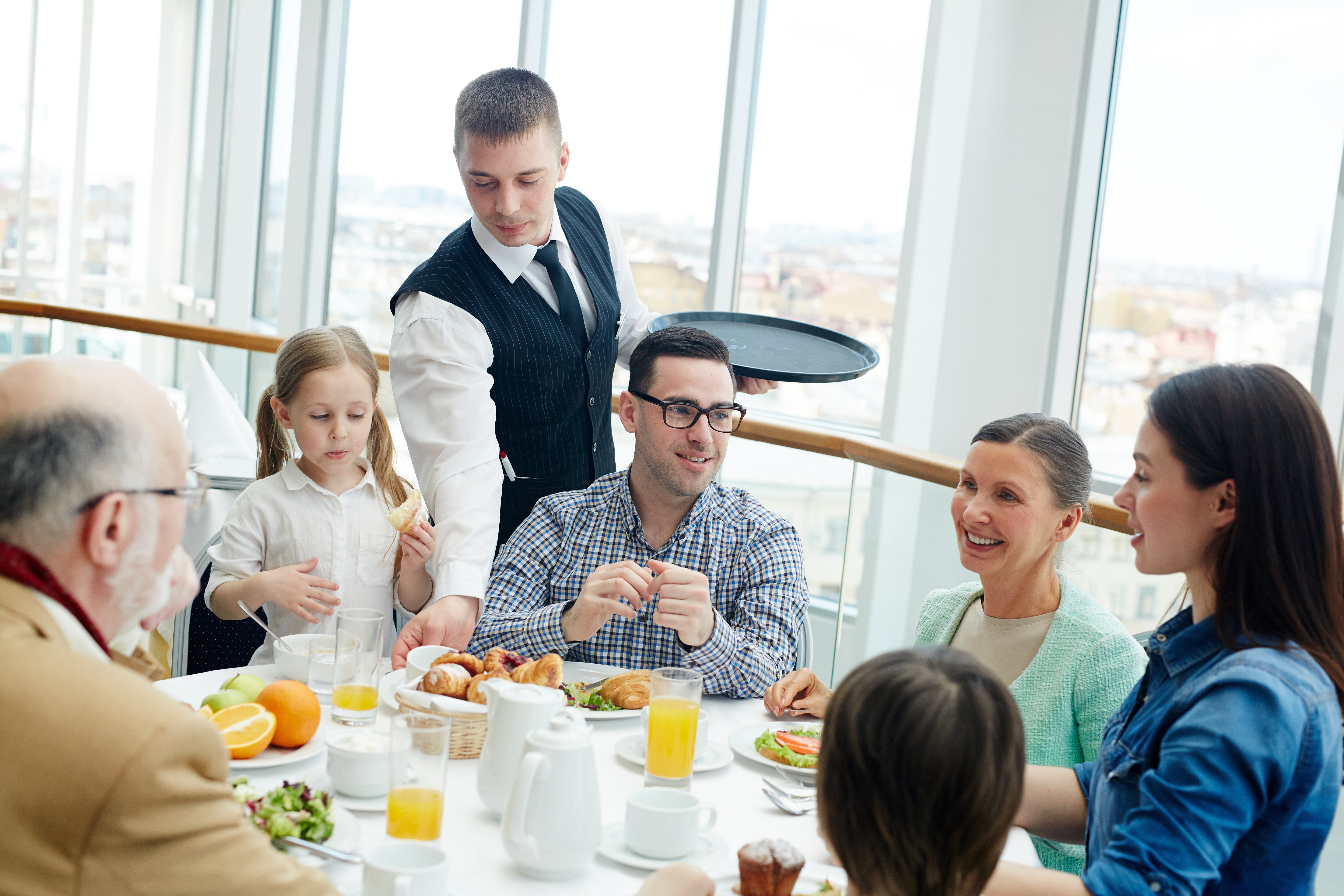 Family eating at a restaurant and waiter with tray